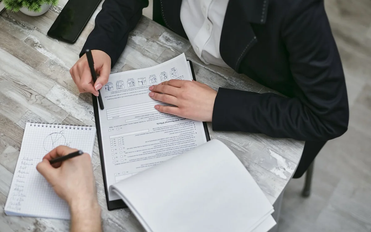 Two people reviewing and signing paperwork at a desk